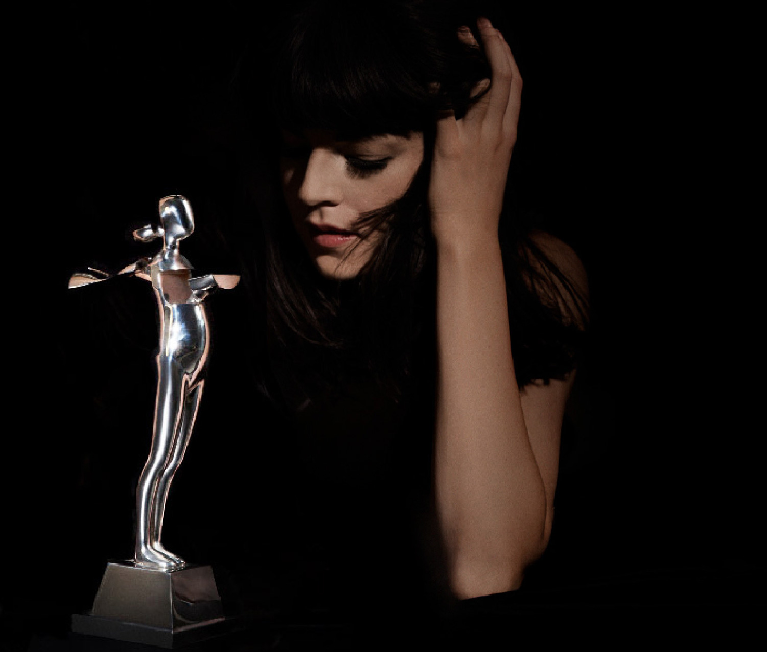 A model posing alongside a trophy replica of a sculpture by Ernest Trova for the Council of Fashion Designers of America CFDA